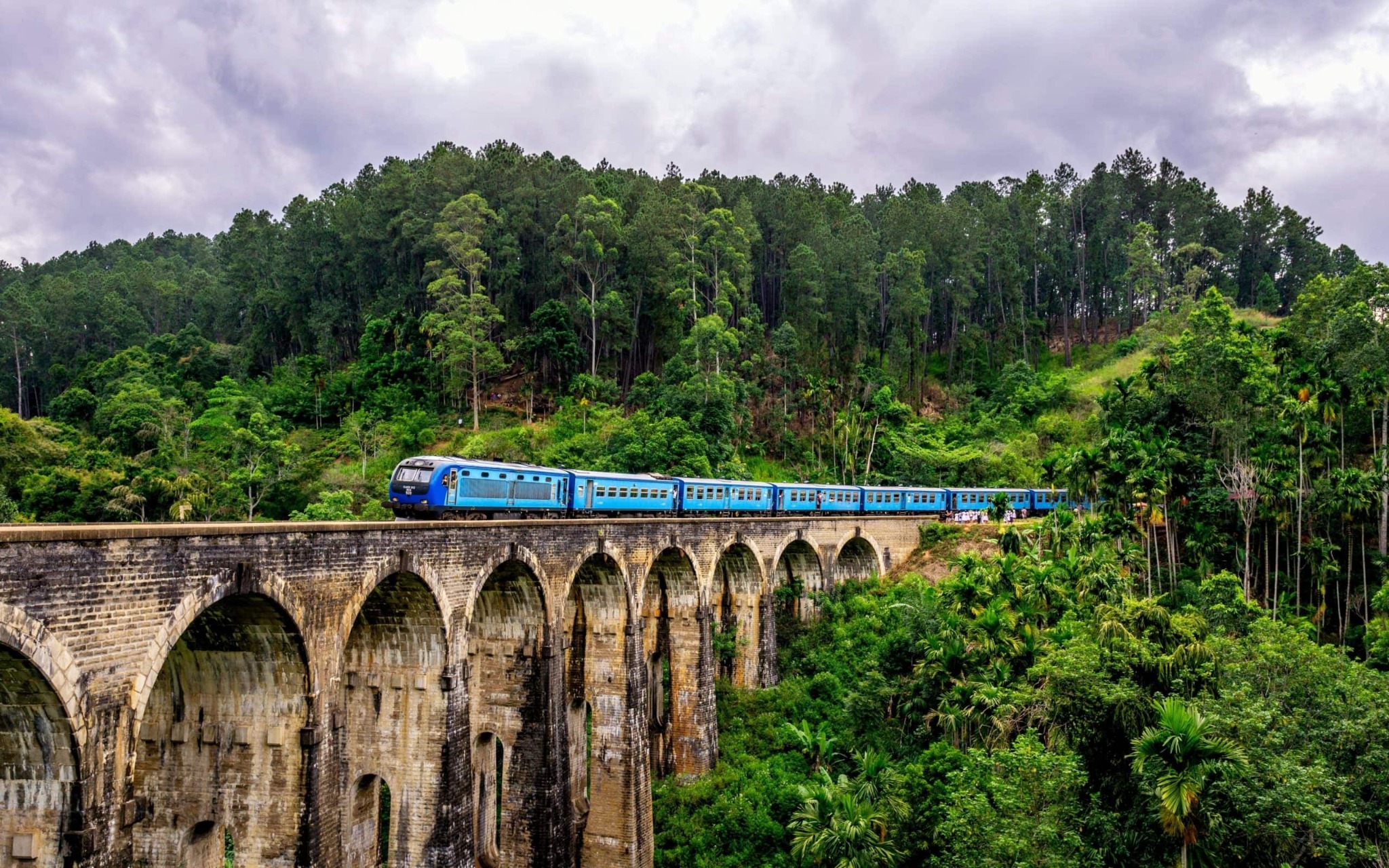 A blue train crossing the Nine Arches Bridge in Sri Lanka